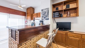 A modern kitchen with a wooden island, a built-in TV, and a brick accent wall. - GuestReady - Urban escape with a view (Porto)