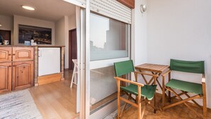 A compact kitchen with wooden cabinets, a refrigerator, and a dining area with a table and two chairs. - GuestReady - Urban escape with a view (Porto)