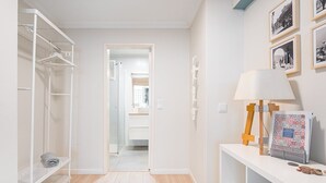 A hallway with a white wardrobe, a mirror, and a lamp on a stand. There are framed pictures on the wall. - GuestReady - Porto by Pilar Ridge (Vila Nova de Gaia)
