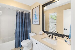 A bathroom with a bathtub, toilet, sink, and a large mirror.