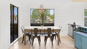 Un comedor con una mesa y sillas, una araña y vistas por un ventanal amplio.