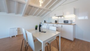 Una cocina moderna con armarios blancos, una mesa de comedor y un techo alto con vigas a la vista.