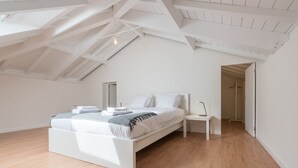 Un dormitorio moderno con una cama blanca, una mesita de noche y un vestidor.