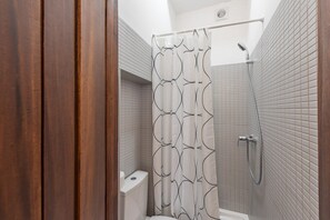 A modern bathroom with a shower, toilet, and a wooden door. - GuestReady - Clerigos-Virtudes Apartments (Porto)