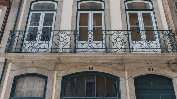 A multi-story building with a balcony, large windows, and doors.