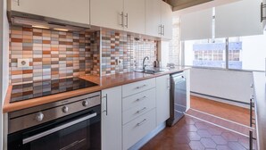 A modern kitchen with a tiled backsplash, stainless steel appliances, and a view to the outside. - GuestReady - Urban escape in Porto (Porto)