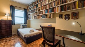 A bedroom with a bed, a desk, a chair, a dresser, and a bookshelf filled with books. - GuestReady - Urban escape in Porto (Porto)