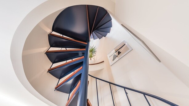 Un escalier en colimaçon moderne au design minimaliste, avec une palette de couleurs comprenant le noir et le bois.