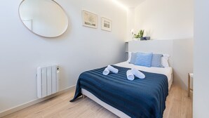 Une chambre à coucher moderne avec un lit, un miroir rond et deux tableaux encadrés accrochés au mur.