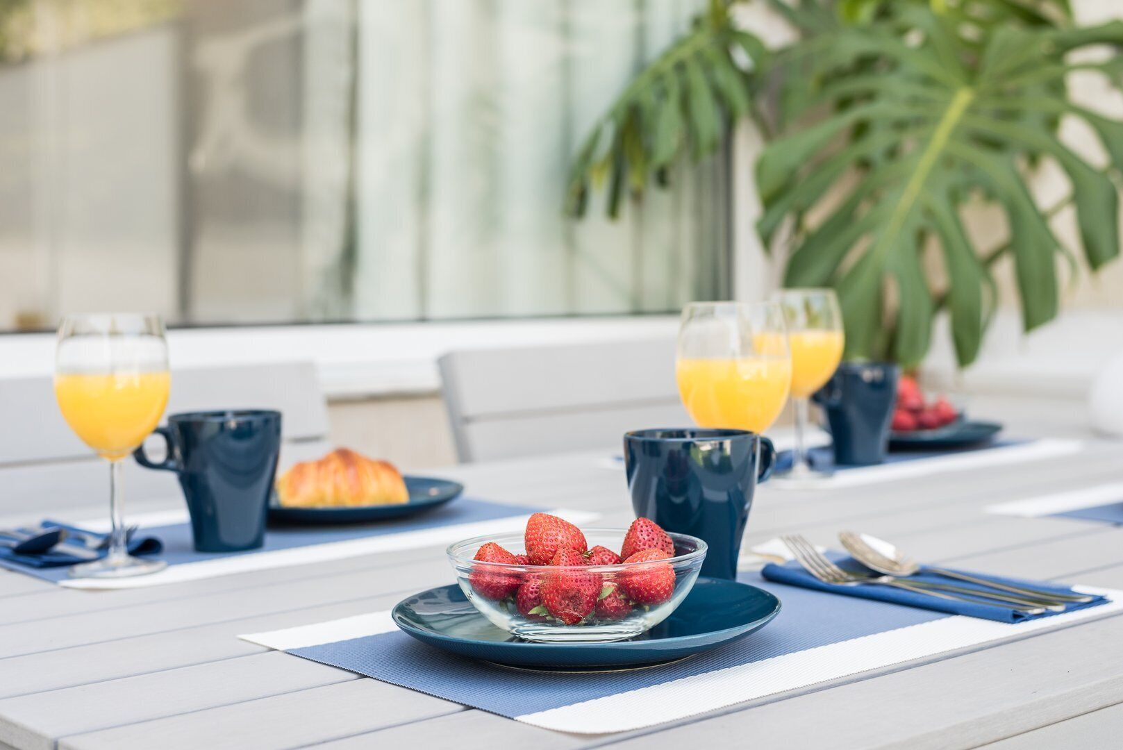 Een ontbijttafel met een croissant, aardbeien en glazen sinaasappelsap.