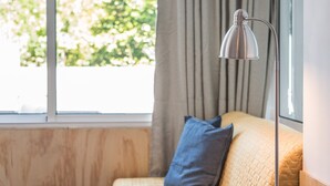 A bedroom with a bed, pillows, a floor lamp, and a window with curtains. - GuestReady - Sunny patio paradise in Porto (Porto)