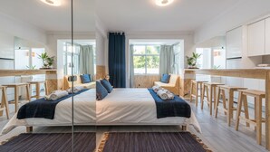A modern hotel room with a large bed, a desk, and a kitchenette. - GuestReady - Sunny patio paradise in Porto (Porto)