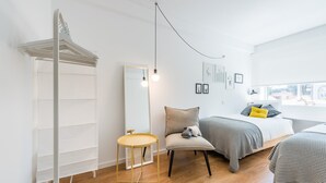 A modern bedroom with a bed, a chair, a small table, and a mirror. - GuestReady - Chic and cozy getaway (Porto)