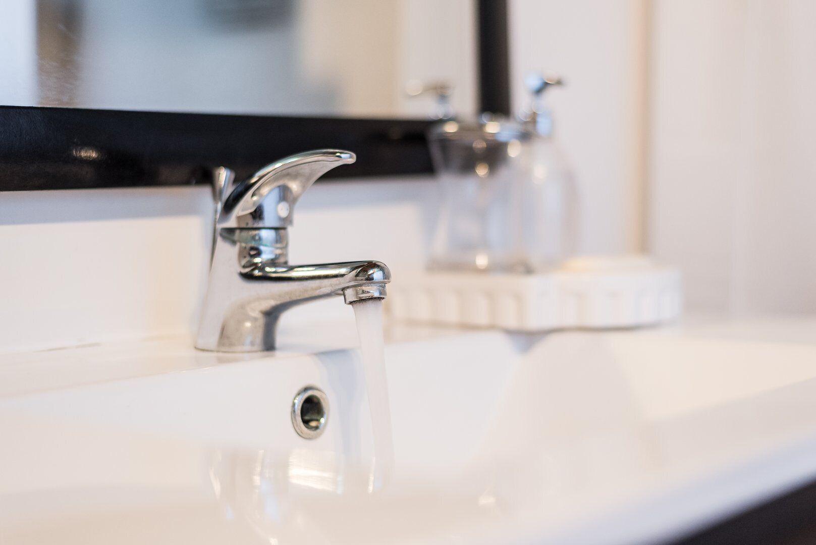 Un lavabo de salle de bain moderne, doté d’un robinet chromé et d’un miroir placé au-dessus.