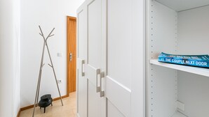 Ein Zimmer mit weißen Schränken, einer Holztür, einer Metallleiter und einem Regal mit dem Buch „The Couple Next Door“.