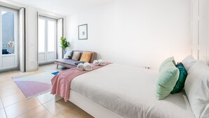 Ein modernes Hotelzimmer mit einem großen Bett, einer Couch und Blick ins Freie.
