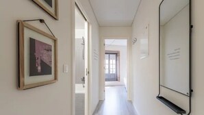A hallway with framed artwork on the walls, a whiteboard, and a door leading to another room. - GuestReady - Genuine Oporto Apts (Porto)