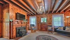 Interior acogedor de una cabaña de troncos con chimenea, televisión, sofá y candelabro.