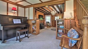 Una sala de estar acogedora con un piano, estanterías, una silla de madera y una escalera.