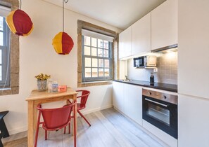 Eine moderne Küche mit weißen Schränken, einem Holztisch, roten Stühlen, einem Fenster und hängenden Papierlampen.