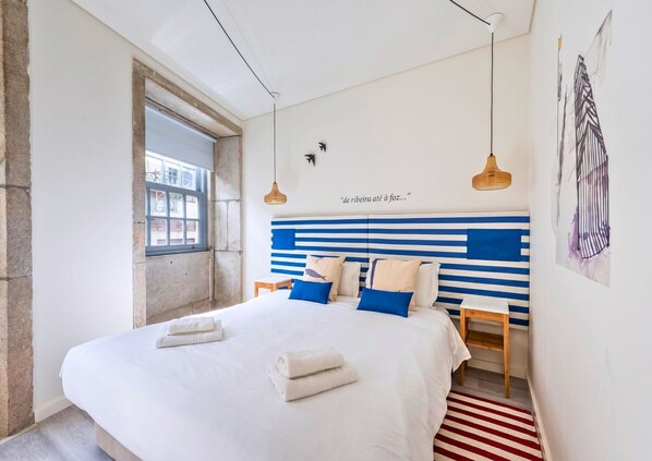 Ein Schlafzimmer mit einem Bett, einem Nachttisch, einem Fenster und einer Wand mit einem Zitat.