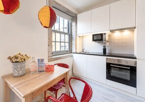 A modern kitchen with white cabinets, a black microwave, and a built-in oven. - GuestReady - Genuine Oporto Apts (Porto)