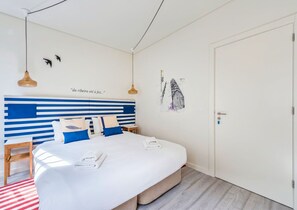 Une chambre à coucher avec un lit, des tables de chevet, une porte et des œuvres d’art murales.