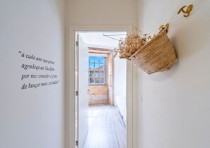 Un couloir avec un panier fixé au mur et une citation en portugais.