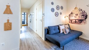 Una sala de estar moderna con un sofá azul oscuro, un tapiz estampado y platos decorativos en la pared.
