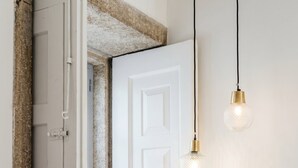 Een witte deur met een textuurrijke stenen muur erboven en een hangende lamp.