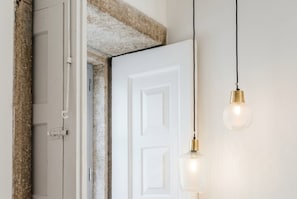 Une porte blanche, avec un mur en pierre à texture au-dessus et un luminaire suspendu.