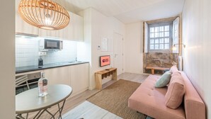 Een moderne keuken met een magnetron, een eettafel met stoelen, een bank met kussens, een houten bankje en een bordje met de tekst 'GUEST READY'.