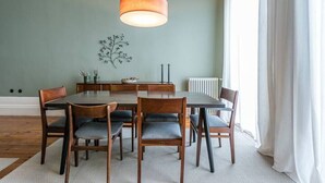 A dining area with a wooden table and chairs, a pendant light, and a wall-mounted decoration. - GuestReady - Picaria Living Quarter 1 (Porto)