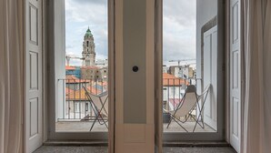 Une chambre avec vue sur un beffroi historique et des bâtiments aux toits rouges.