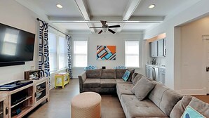 Una sala de estar con un sofá modular, un reposapiés y un mueble de entretenimiento.