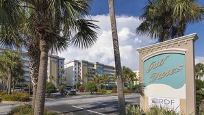 A hotel entrance with palm trees and a sign for 'Duke Dunes'. - Fort Walton Beach Condo | Complimentary Seasonal Beach Service & More! (Fort Walton Beach)