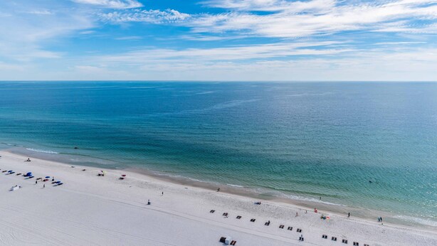 Ein Strand mit weitem Sandbereich und freiem Blick auf das Meer.
