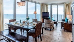 Een ruime woonkamer met een grote eettafel, comfortabele zithoek, een televisie en uitzicht op de oceaan.
