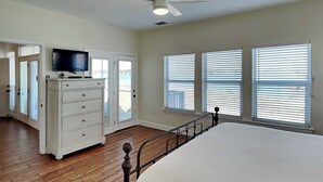 Une chambre à coucher comprenant un lit, une commode, un téléviseur et un ventilateur de plafond.