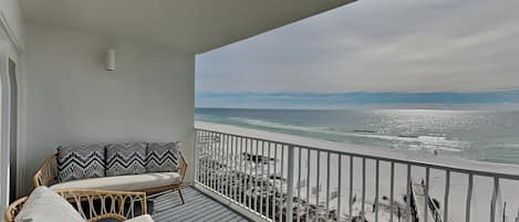 A balcony with wicker furniture and a view of the beach.