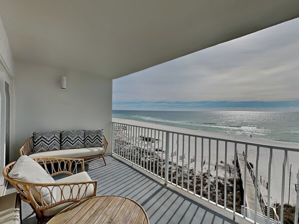 A balcony with wicker furniture and a view of the beach.