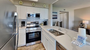 A modern kitchen with white cabinets, stainless steel appliances, and a large island with a sink.