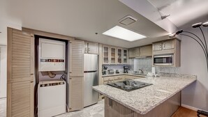 A compact kitchen with a built-in stove, microwave, and a small island with a sink.