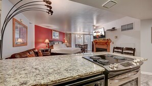 A kitchen with a granite countertop, a stove, and a dining area with a table and chairs.