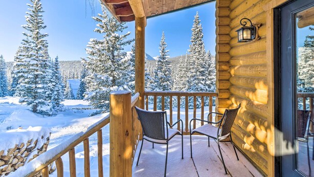 Een houten hut met een balkon, met sneeuw bedekte bomen en een heldere lucht.