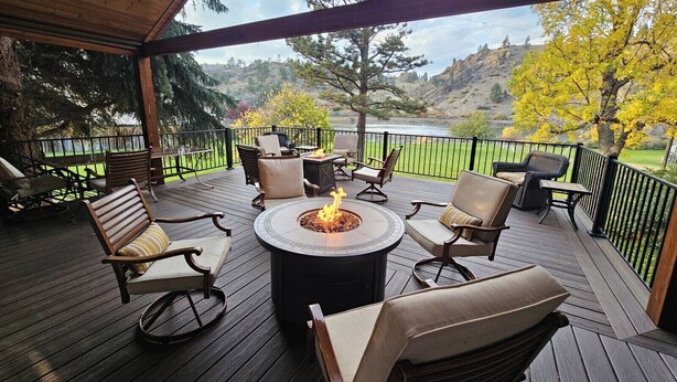 Une terrasse couverte avec des sièges d’extérieur et un foyer, offrant une vue sur un paysage magnifique.