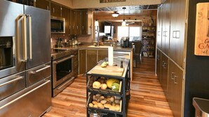 Une cuisine moderne dotée d’appareils électroménagers en acier inoxydable, de meubles en bois et d’un îlot central où sont disposés des produits frais.