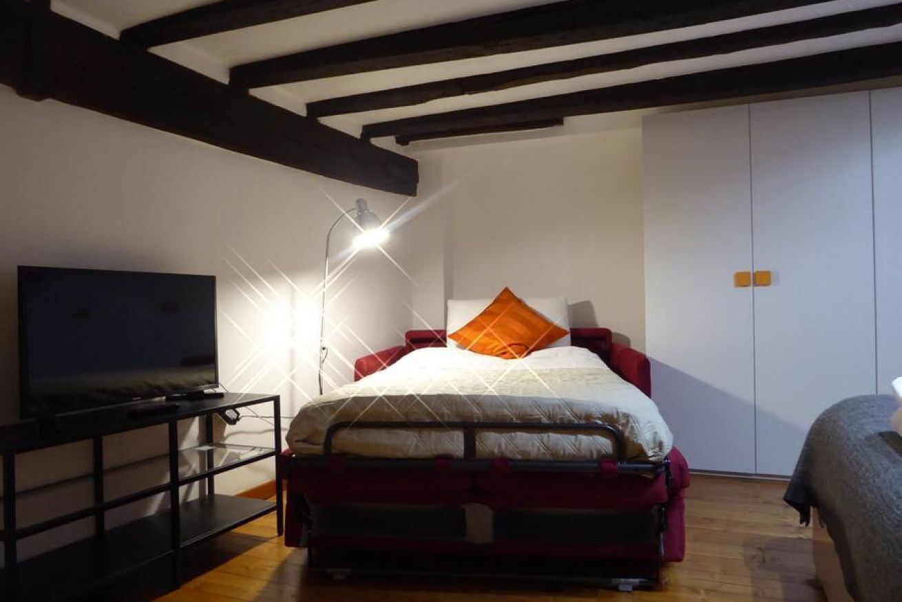 Une chambre à coucher avec un lit, une télévision et une armoire.