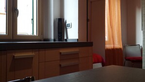 Une cuisine avec des meubles en bois, un four à micro-ondes et une fenêtre avec des rideaux.