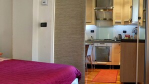 Une chambre compacte comprenant un lit, une petite kitchenette et une salle de bain.